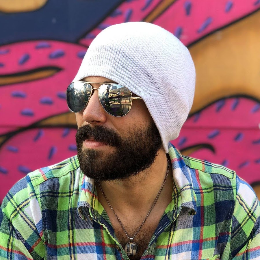 A bearded man wearing a white beanie and sunglasses.