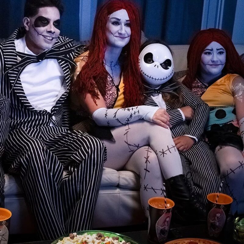 A group of people dressed as jack and sally are sitting on a couch.