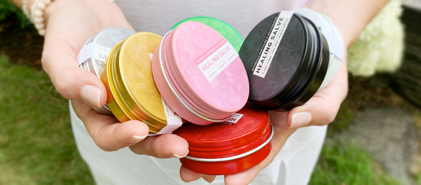 On Small Business Saturday, a woman proudly showcases a variety of vibrant tins she holds in her hands.