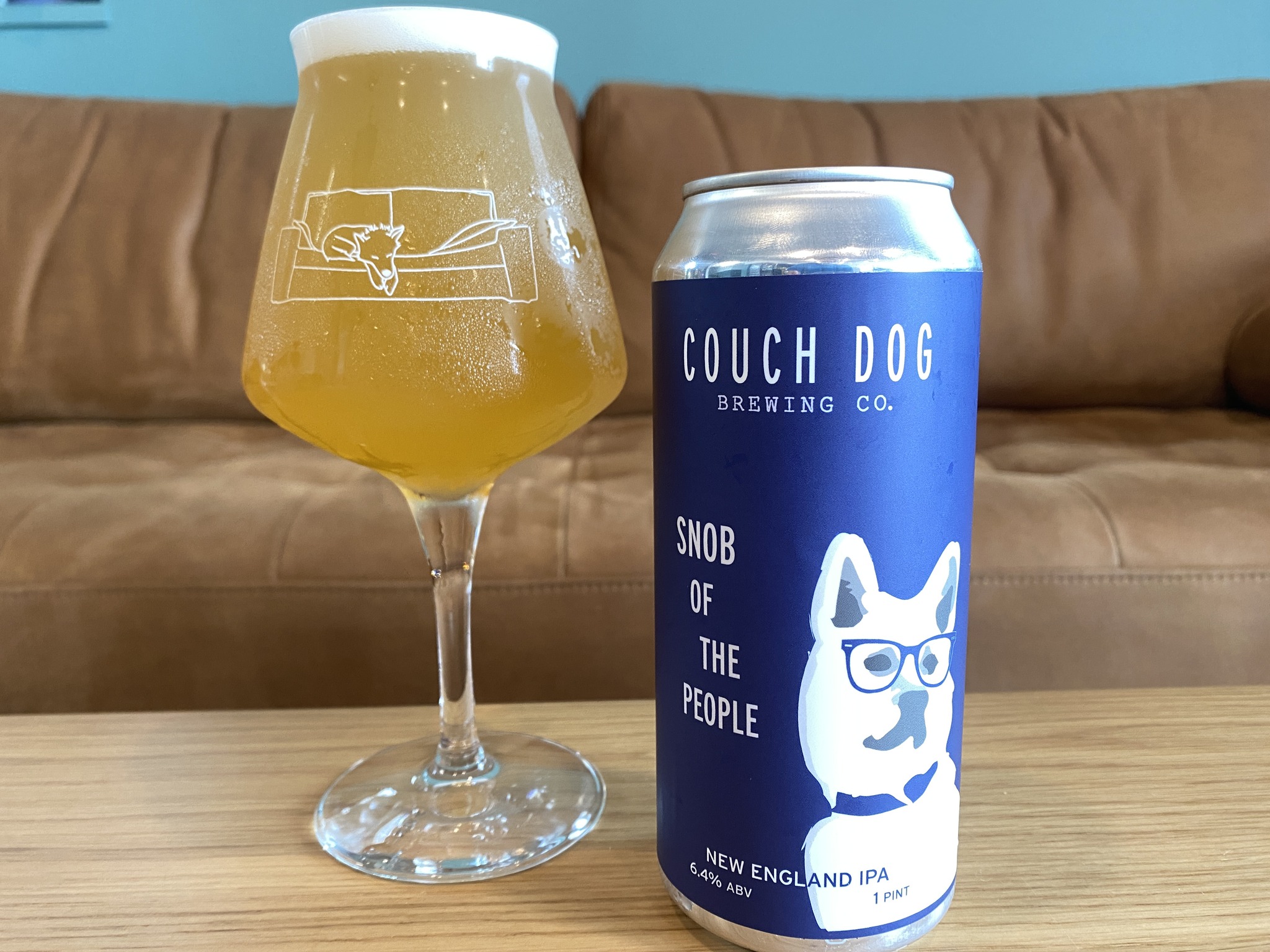 A glass of beer next to a can of couch dog.