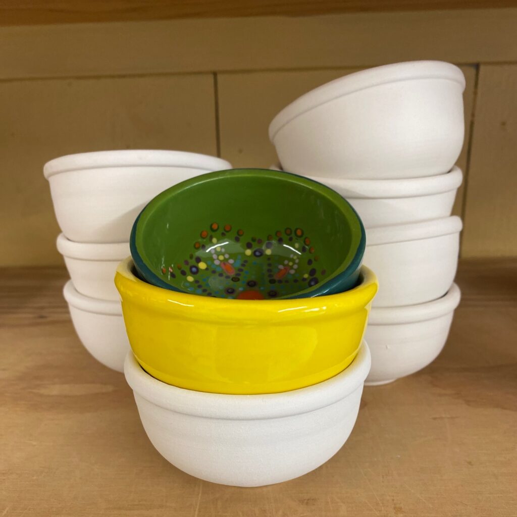 A stack of white and yellow bowls on a shelf, perfect for Small Business Saturday shoppers seeking unique kitchenware.