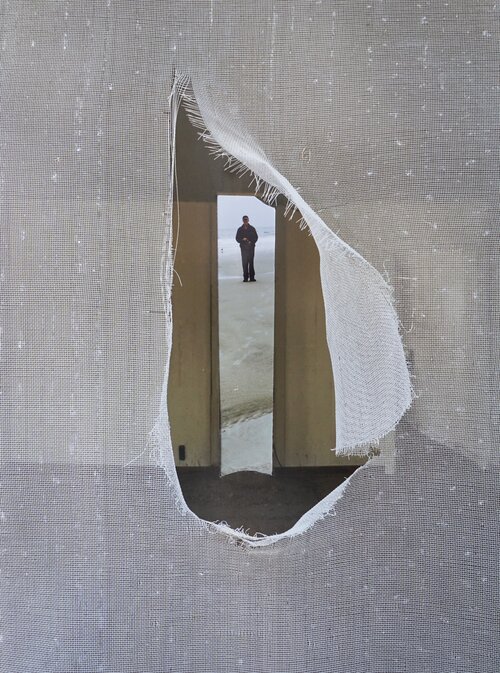 An image of a man standing in a hole in a wall.