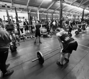 An entrancing monochrome photograph showcases a gathering of individuals actively engaged in a fitness activity within a gym environment.