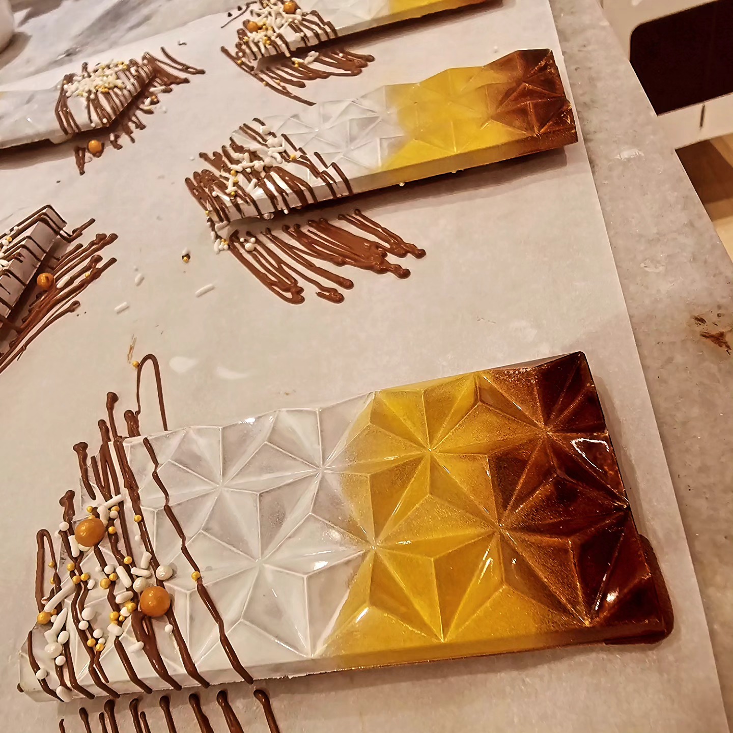 A selection of decadent chocolates are under production on a workspace, expertly crafted to provide the ultimate taste experience.