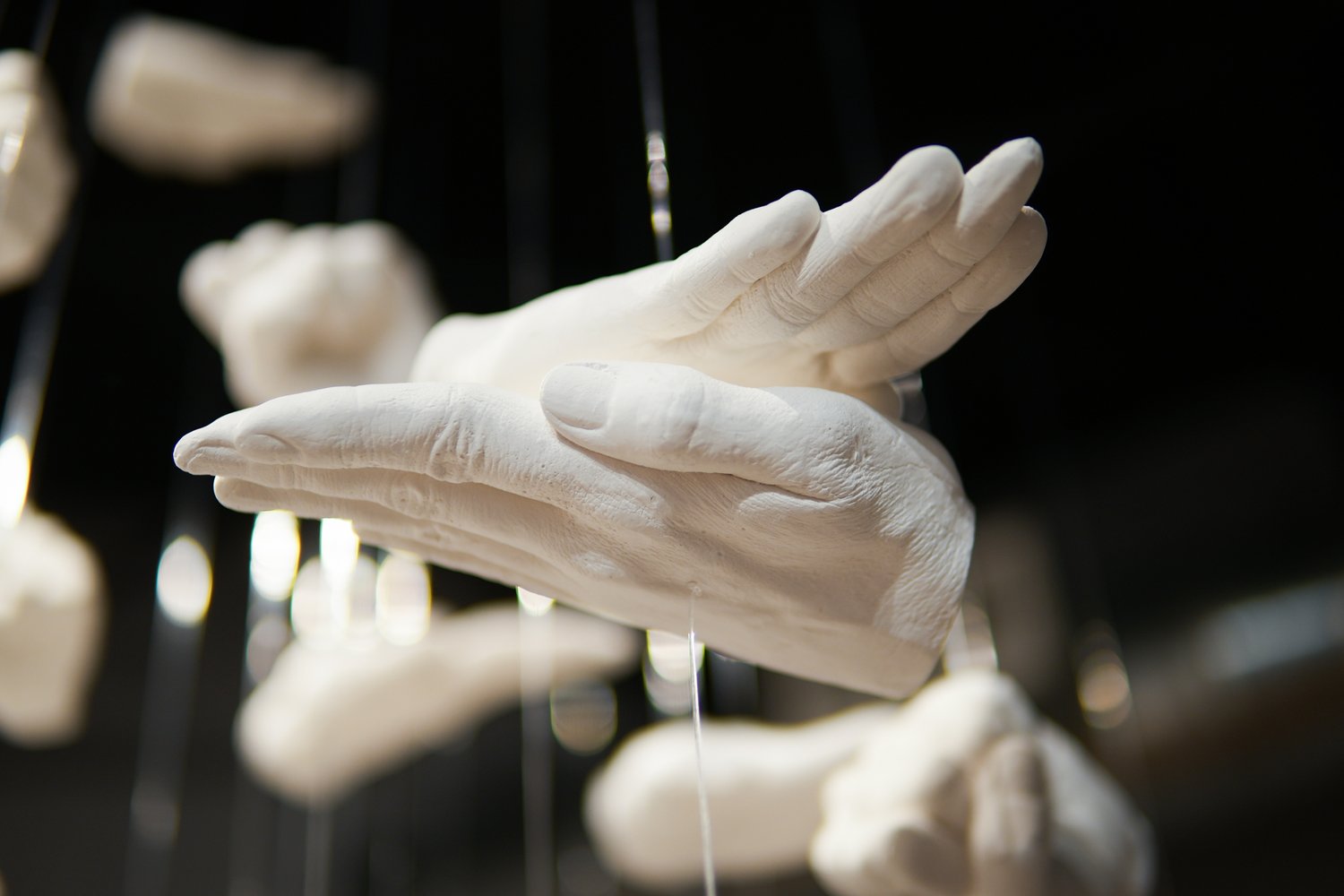 A collection of white hands suspended on a string.