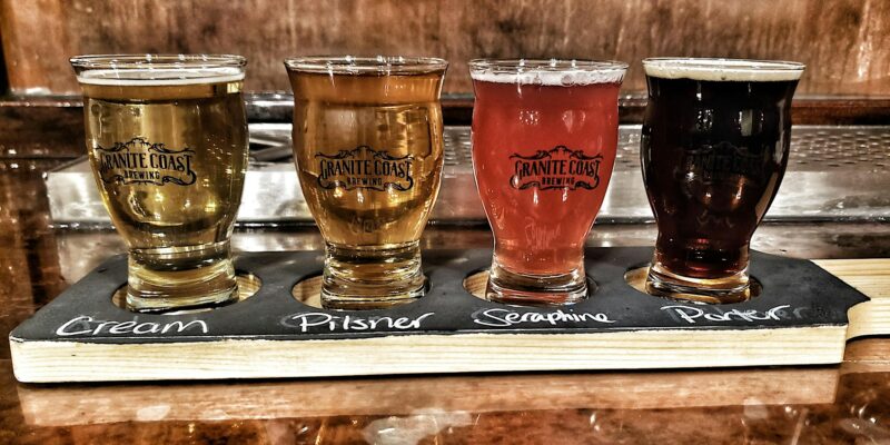 Check out this picture-perfect lineup of four beers, each ready to pour and perfectly positioned on a rustic wooden board.