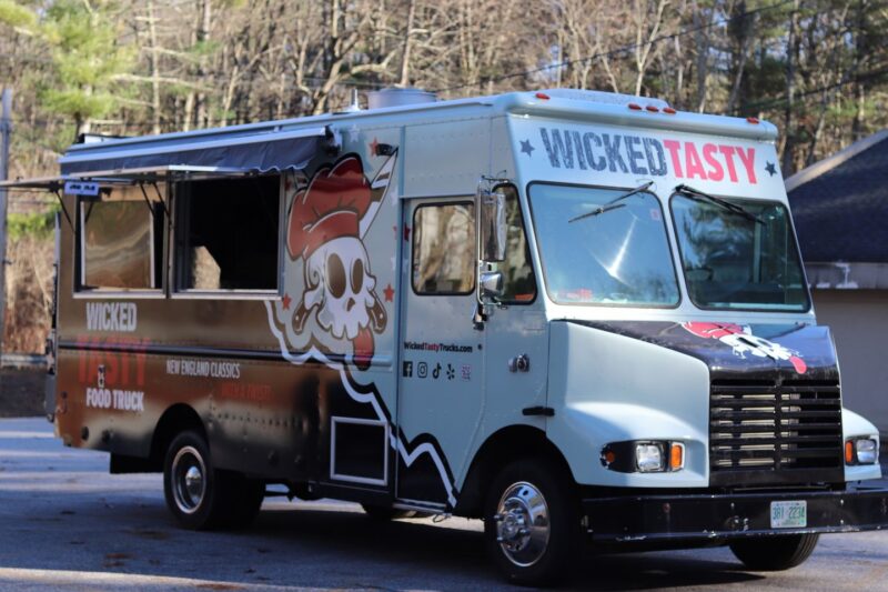 Get ready to enjoy the delectable delights from the "Wicked Tasty" food truck, idyllically stationed for you on this beautiful sunny day.
