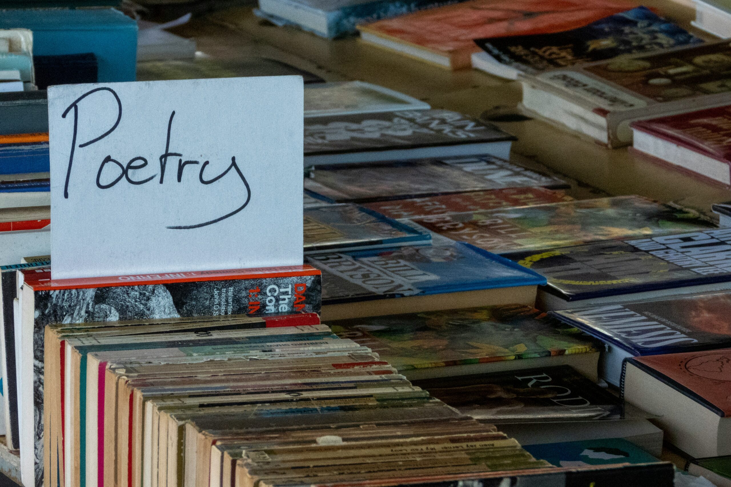 A "poetry" sign stands out on a table filled with a variety of books.