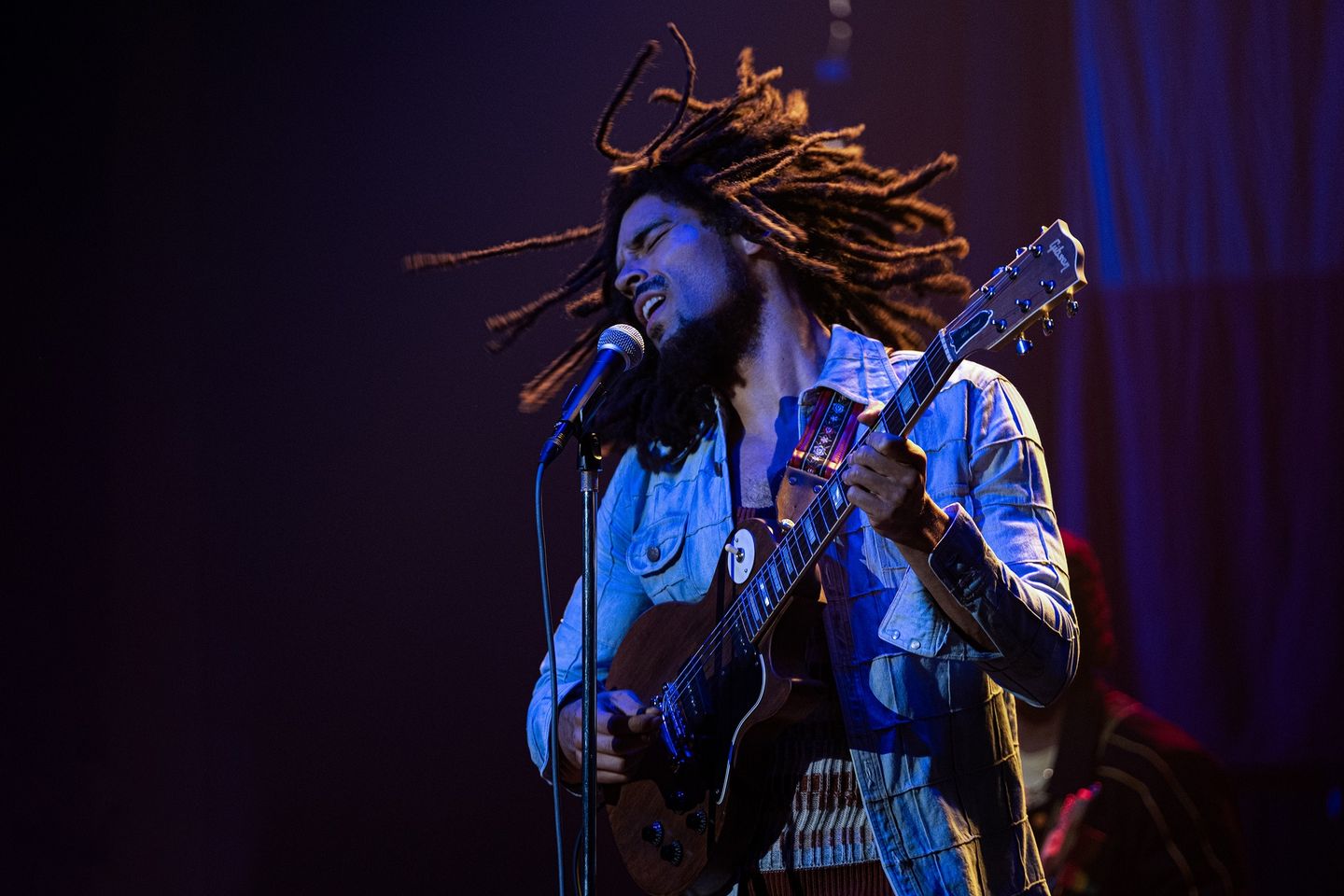 Dreadlocked artist rocking the stage with an electric guitar.