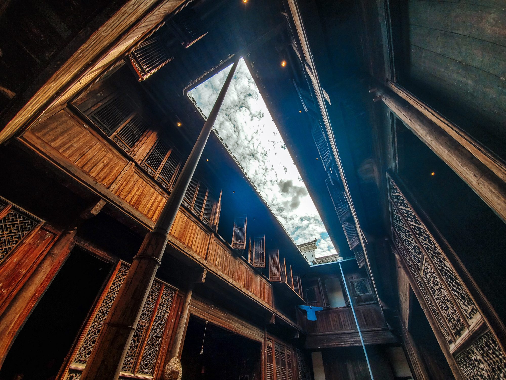 Experience the beauty of the sky peering through a gap in an elaborately designed traditional wooden structure.