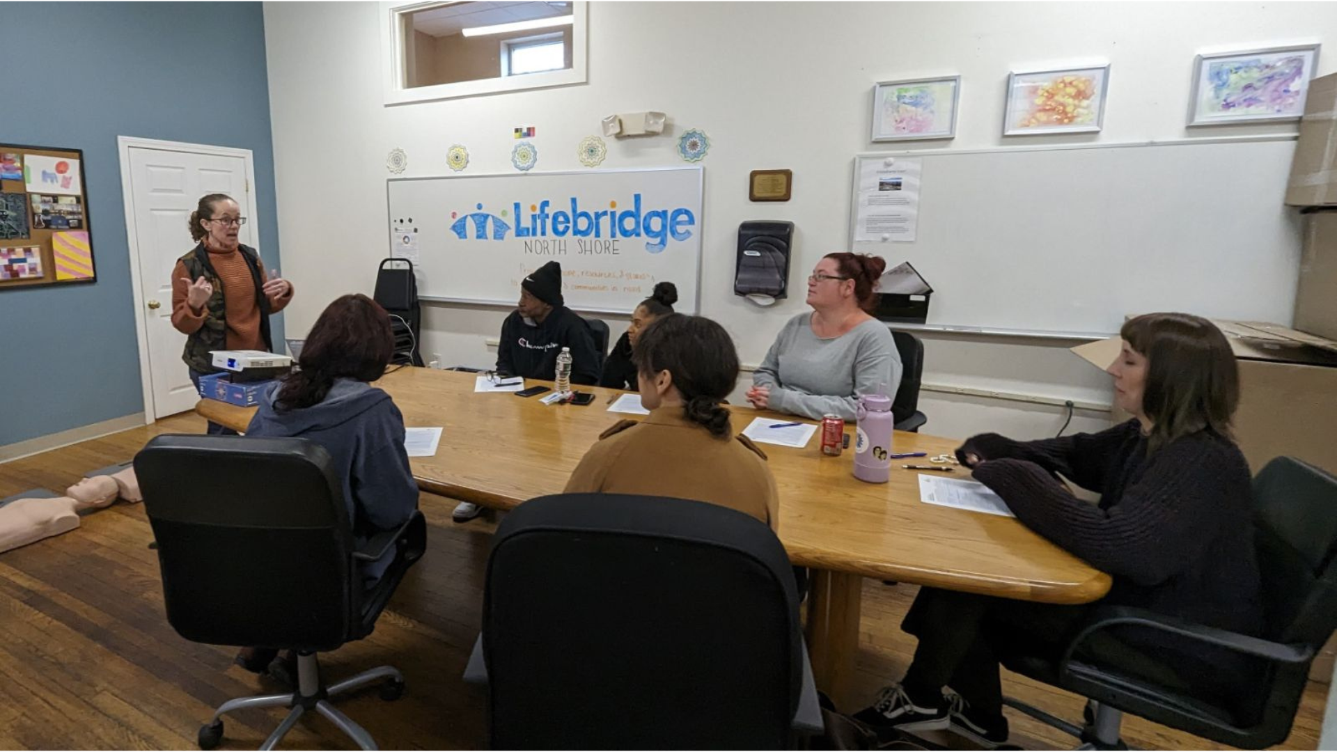 Creative entrepreneurs in Salem, MA, collaborate around a lively table as an instructor inspires; Lifebridge North Shore unites our Essex County community.
