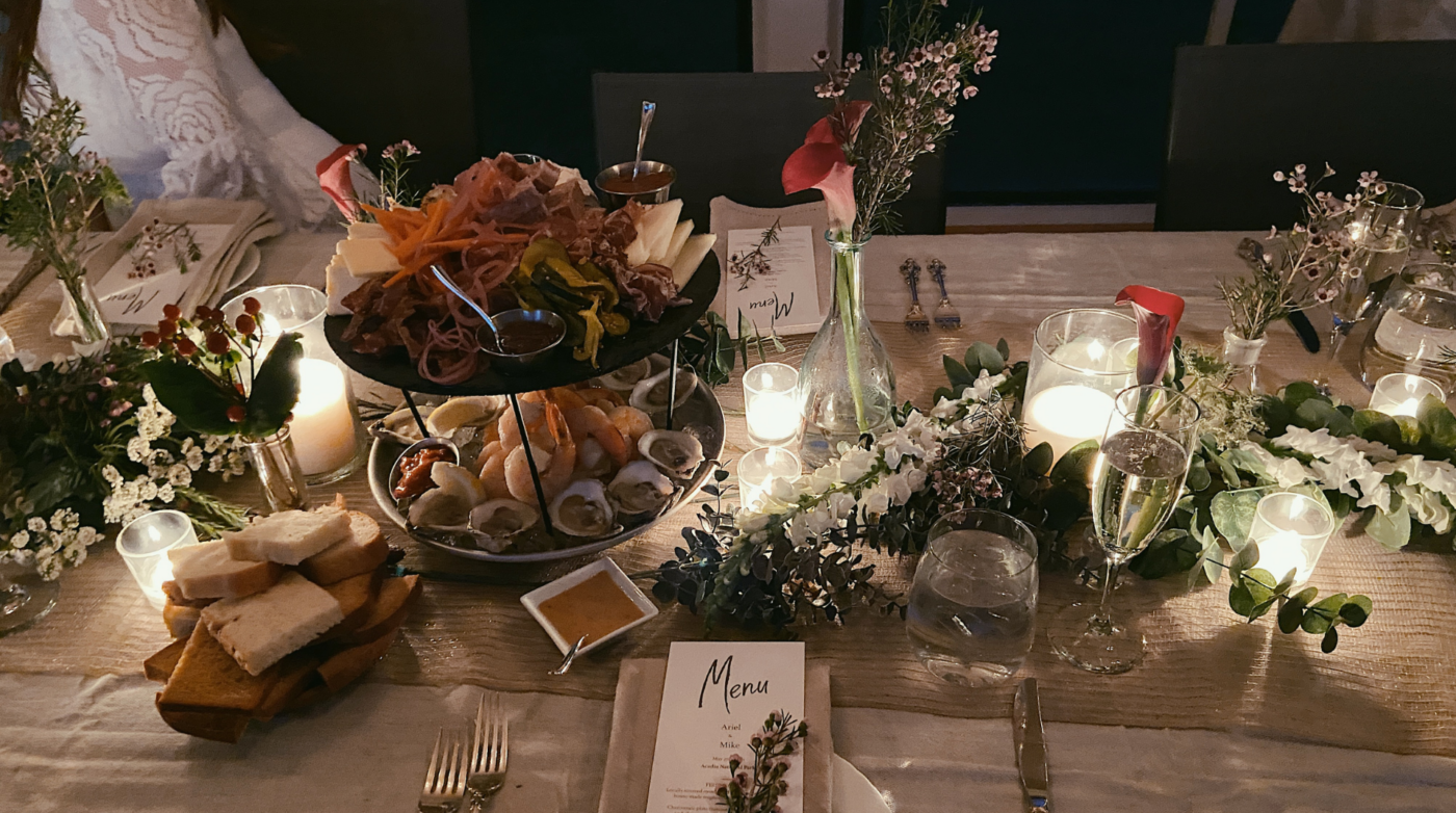 Picture a beautifully set dining table complete with a tempting charcuterie platter, flickering candles, fresh flowers, and elegantly displayed menus. Perfect for creating an inviting atmosphere that entices guests and promises an unforgettable dining experience.