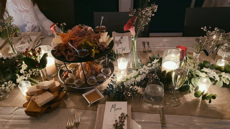 Picture a beautifully set dining table complete with a tempting charcuterie platter, flickering candles, fresh flowers, and elegantly displayed menus. Perfect for creating an inviting atmosphere that entices guests and promises an unforgettable dining experience.