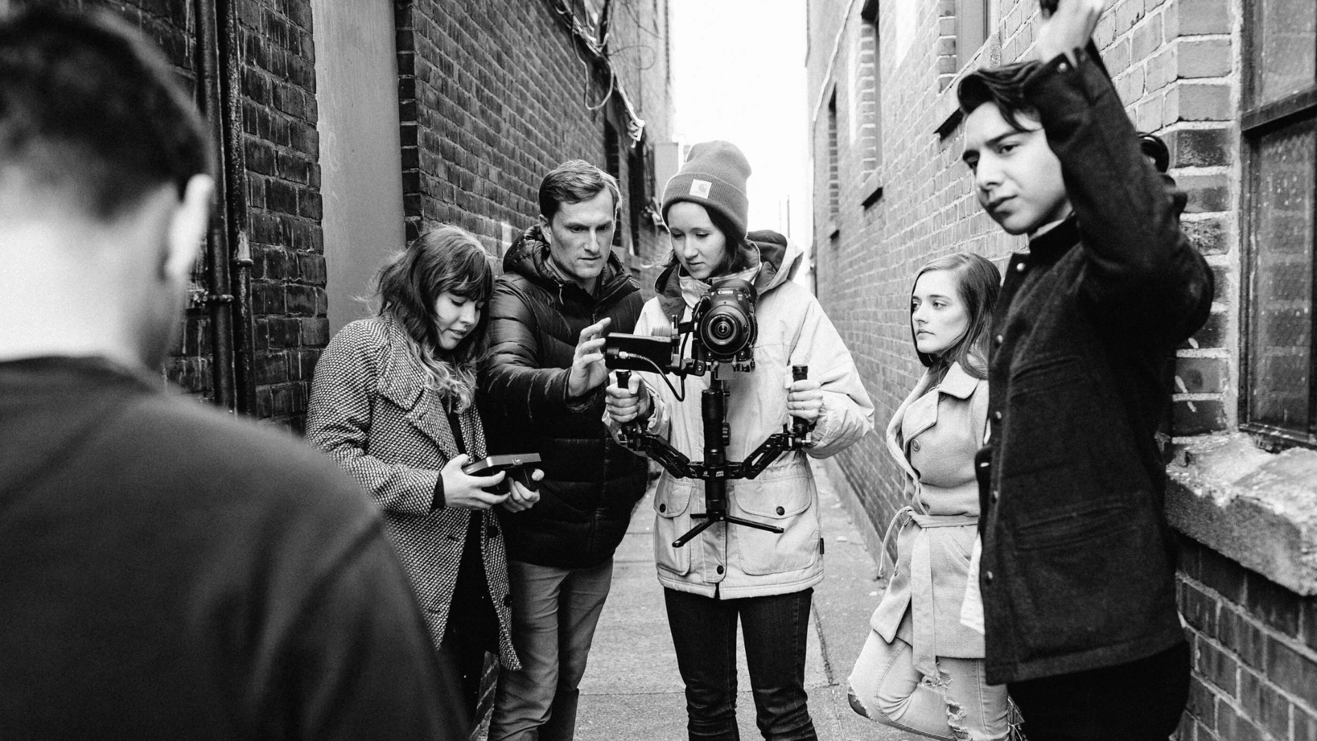 A crew in an alleyway is capturing footage with a camera on a stabilizer, ensuring smooth, cinematic shots.