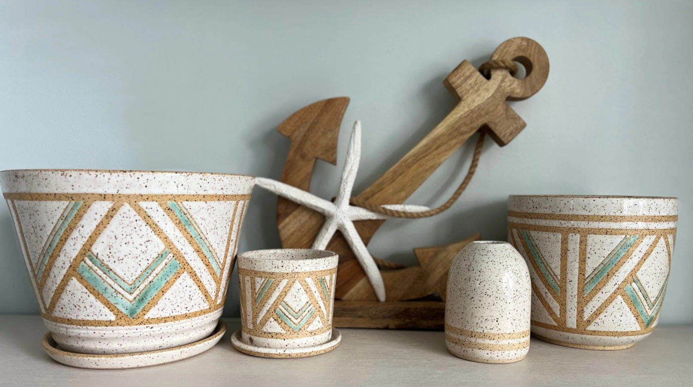 Discover stunning ceramic pots featuring eye-catching geometric designs, beautifully showcased alongside a rustic wooden anchor and a charming white starfish decor piece.