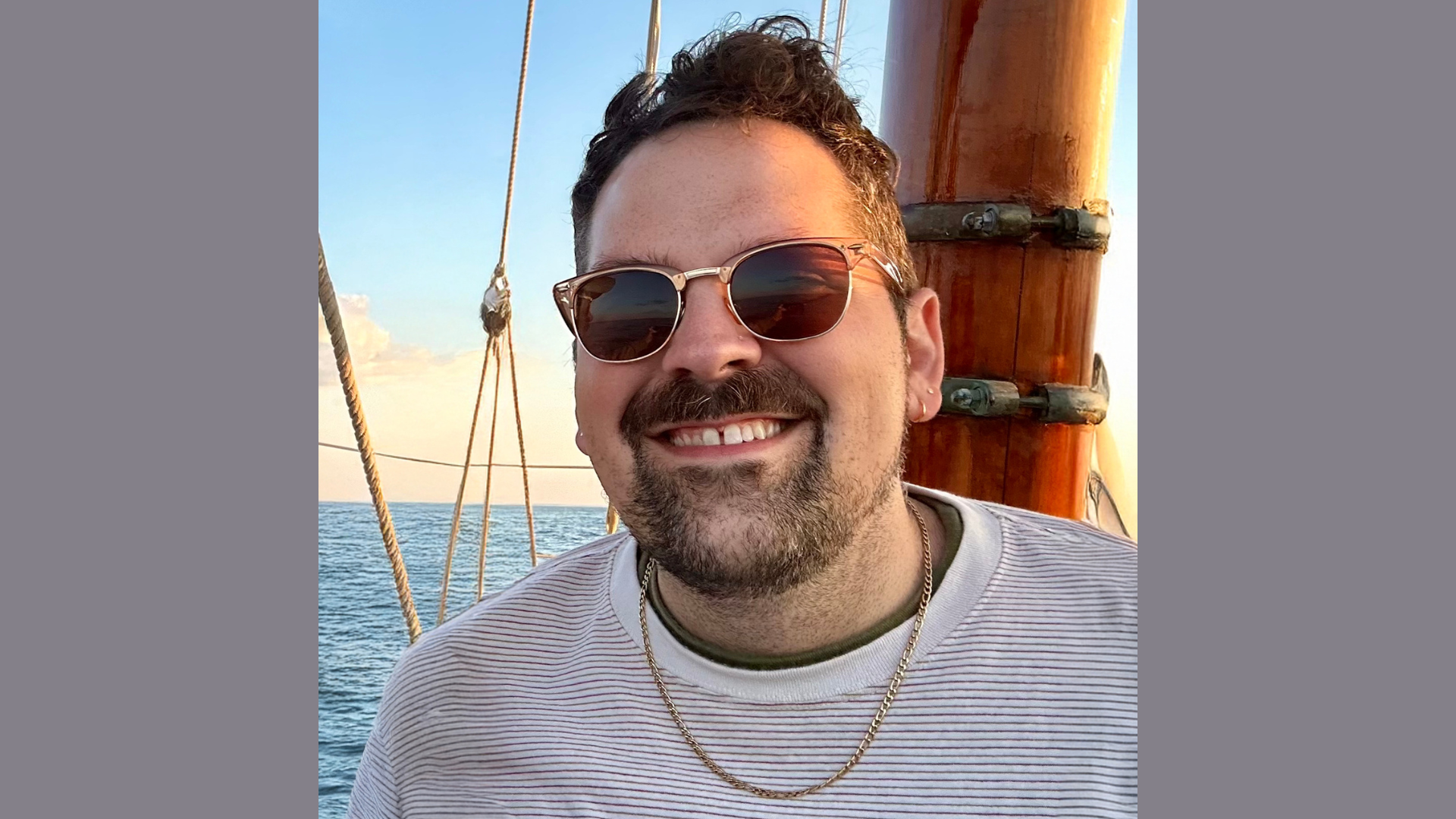Capture the adventurous spirit of Meet the Member: BomBom Beads with this vibrant scene—a man smiling in sunglasses, enjoying life on a boat with the ocean and sky framing his journey.