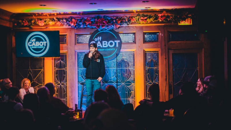 Catch a comedian lighting up the stage at Off Cabot Comedy & Events! Enjoy a night of laughter while seated around intimate tables, perfect for an unforgettable comedy experience.