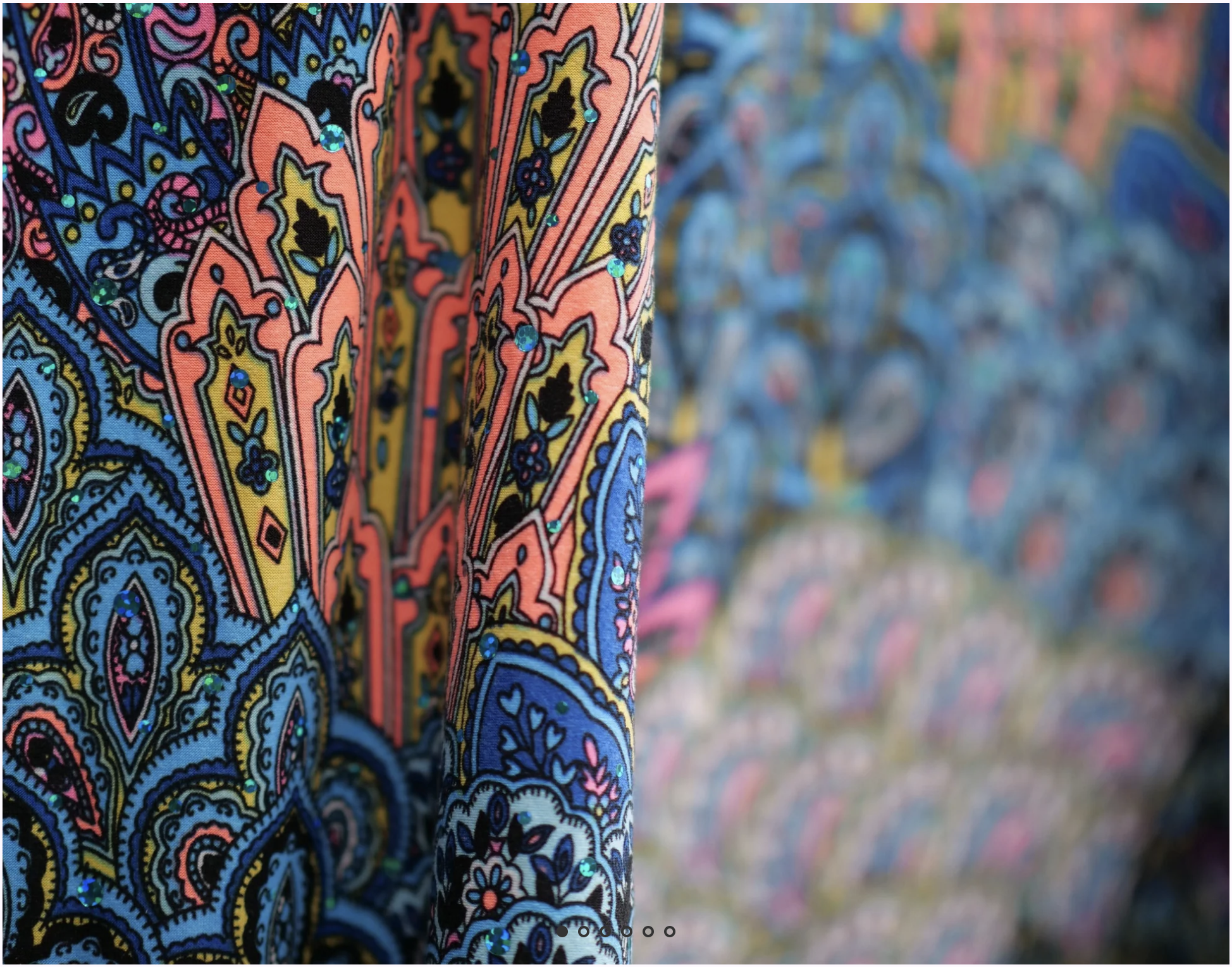 Experience the vibrant essence of Salem's fashion show fundraiser for women's housing with our stunning close-up of colorful fabric. This intricate paisley pattern bursts with blue, orange, pink, and yellow hues, embodying the lively spirit of the event.