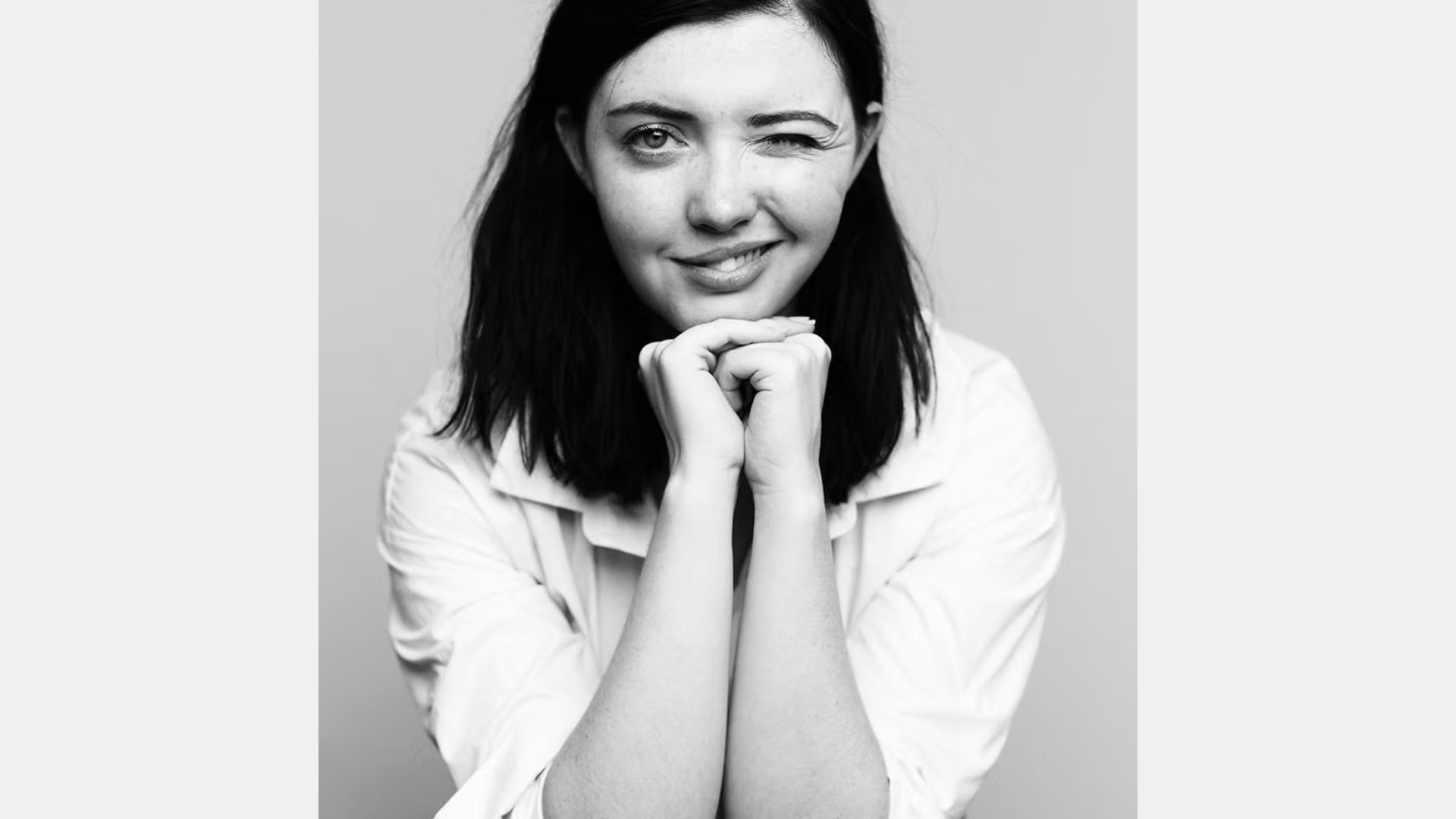 Introducing Our Featured Member: With shoulder-length dark hair and a charming wink, this individual delights the camera with their natural charisma and Glamour Possum allure. The simple background keeps all eyes on their captivating presence.