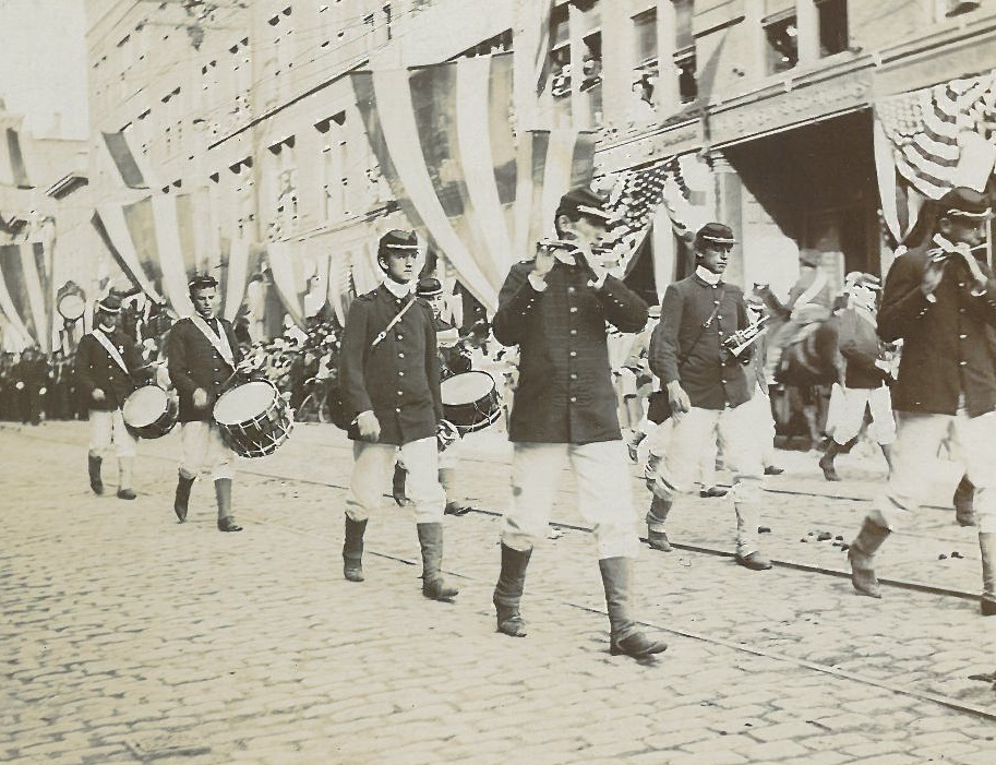 A lively marching band, dressed in sharp uniforms, parades down a charming cobblestone street, filling the air with vibrant music. The surrounding buildings add to the festive scene with colorful banners and flags waving in the breeze.