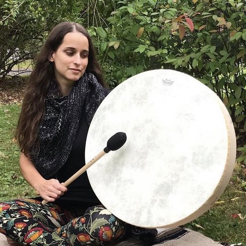 Imagine finding tranquility in nature as you sit outdoors, surrounded by lush greenery, with a large hand drum and mallet in hand. This scene invites a sense of peace and connection to the earth, making it perfect for promoting mindful living or wellness products online. Share this imagery to inspire others to seek their own serene moments in nature.
