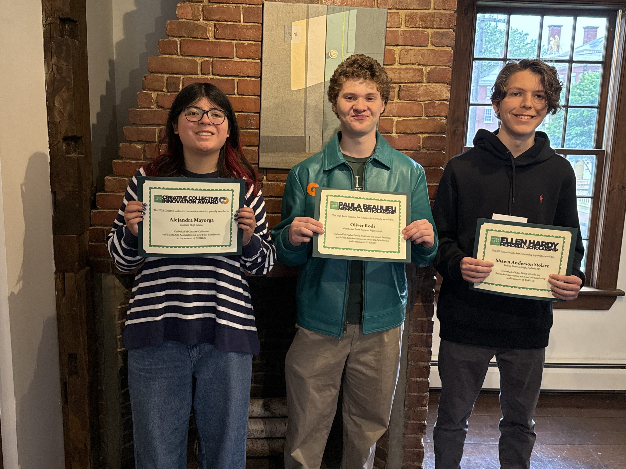 Three smiling teens beam with North Shore art scholarships in hand, sunlight and local art shining behind our vibrant community winners.