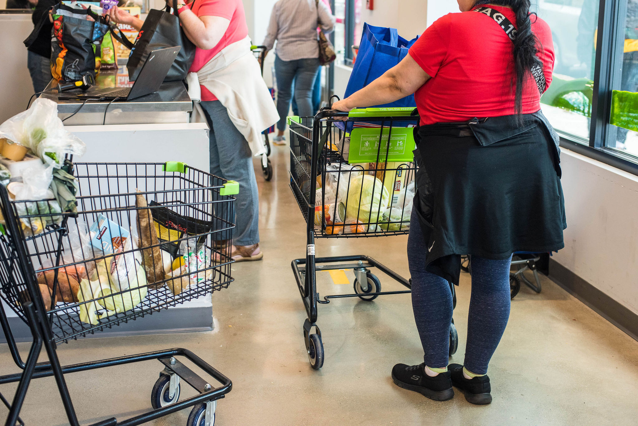Customers line up at our sunlit checkout, carts brimming with fresh finds—neighbors chatting as local energy fills the air.