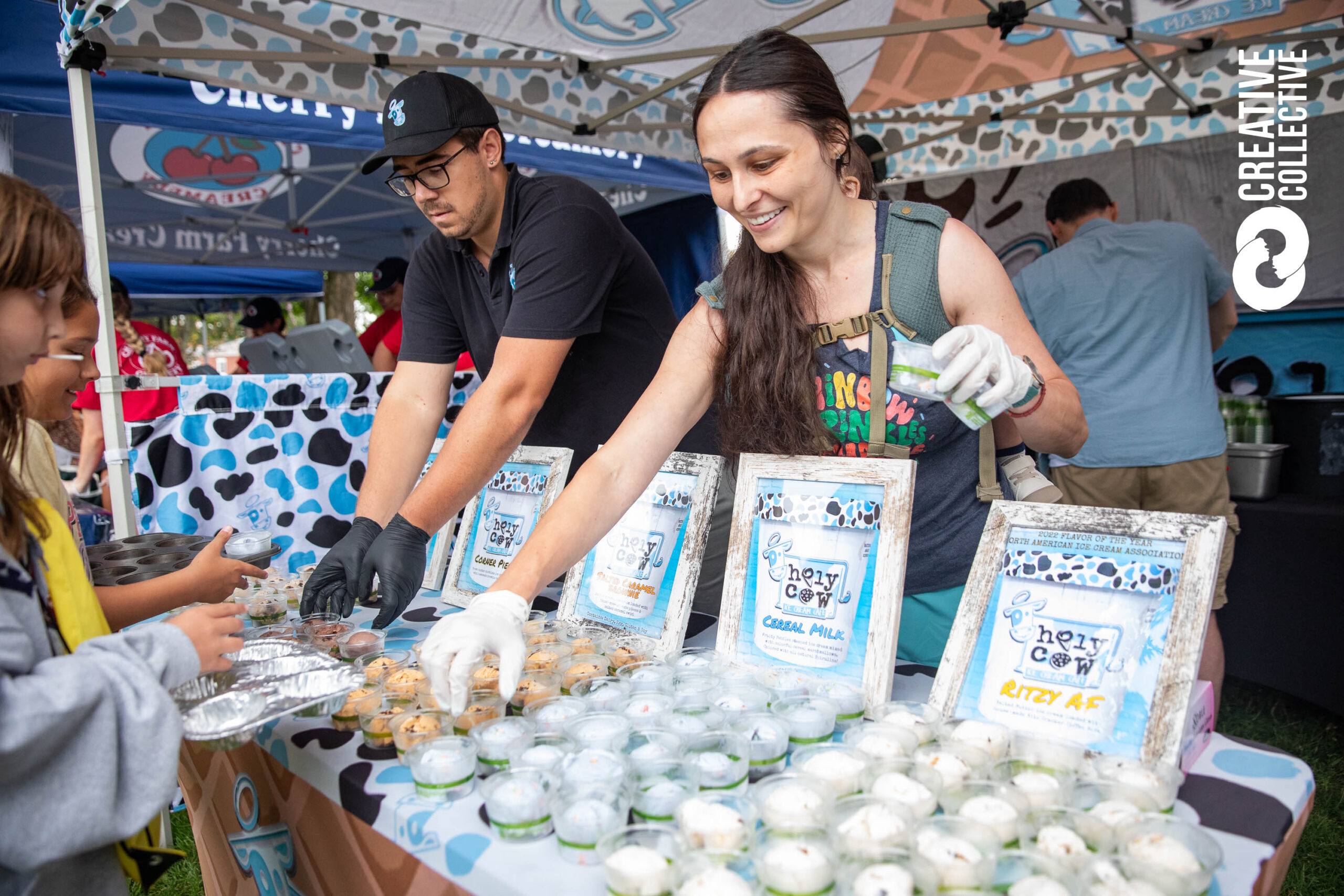 A woman and man share creative Chezy Cow samples at a lively Essex County event, connecting with the community over local flavors.