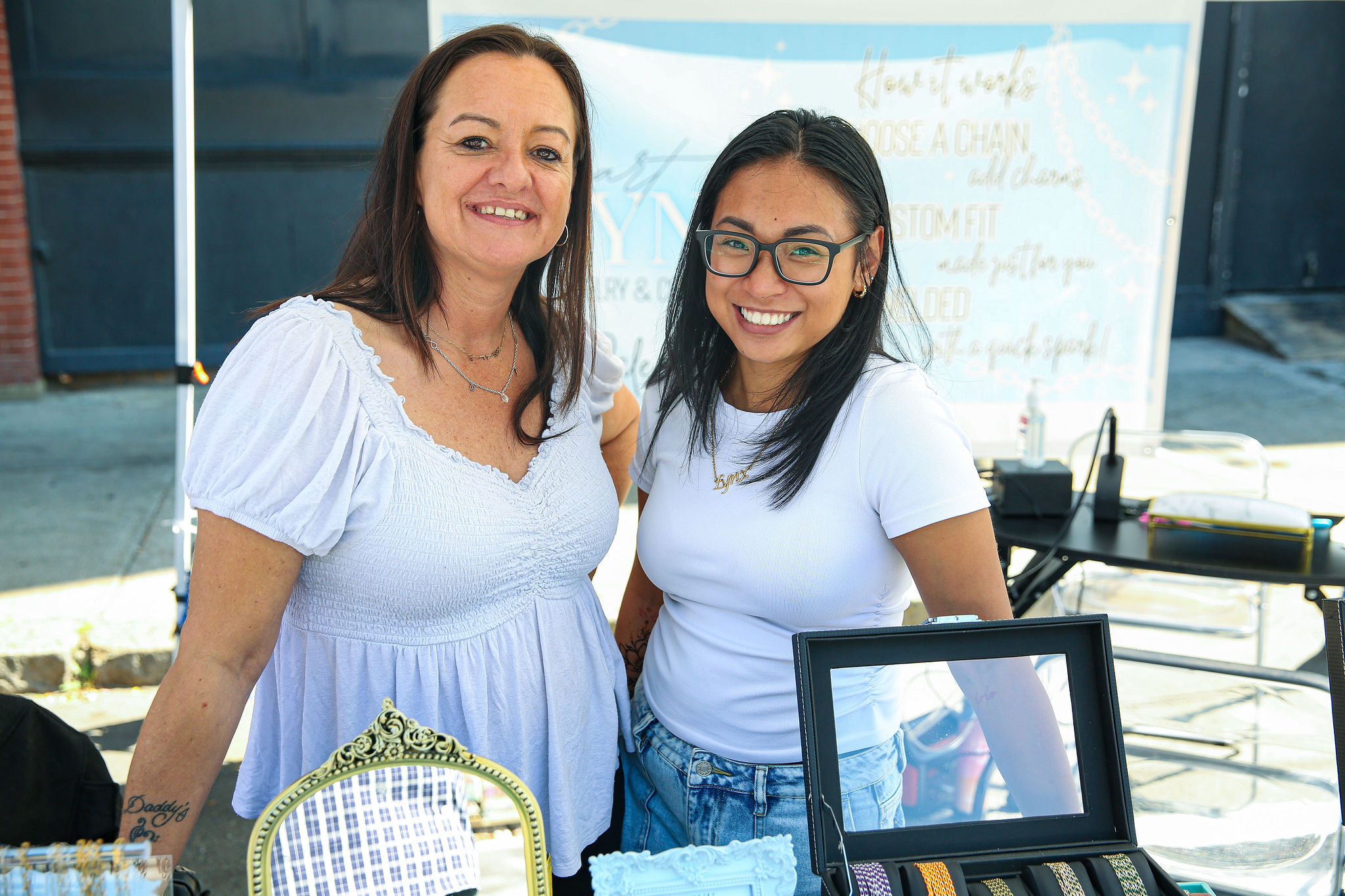 Two women beam behind a vibrant jewelry table at Peabody International Festival 2025, celebrating Essex County’s creative spirit.