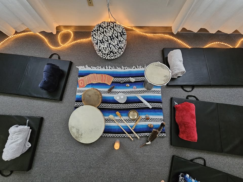 Overhead view of a lively Essex County sound healing circle, with mats, drums, bowls, chimes and glowing string lights inviting community connection.