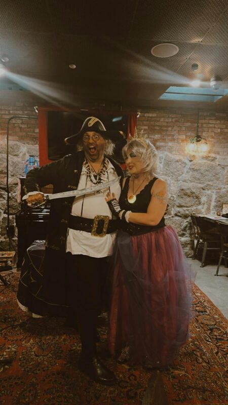 Two adults in creative costumes share a joyful moment indoors, bringing Essex County’s community spirit and fun to life.