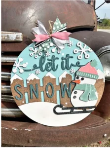 A cheerful “let it snow” sign, decked with a snowman and bright ribbon, brings festive spirit to an old truck—a touch of Essex County creativity.