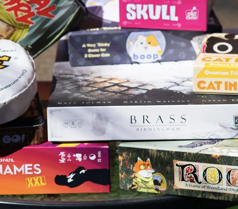 A lively stack of colorful board games—Brass Birmingham, Root, Skull and more—showcases Essex County’s creative gaming spirit.