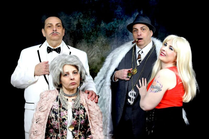 Four vibrant Essex County creatives unite: a man in white suits up, an elder leads front, a stylish gent with cigar beams, all beside our bold woman in red.
