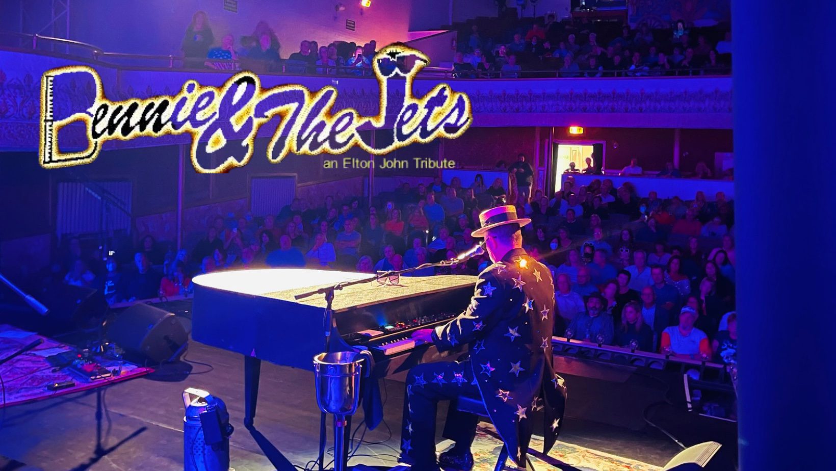 A vibrant performer in a starry suit electrifies the stage on grand piano, energizing the crowd at Essex County's Elton John tribute event.