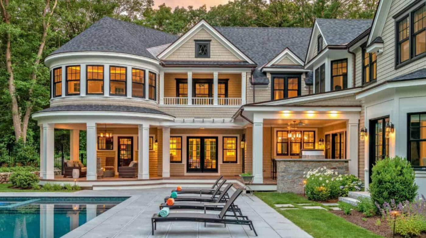 A lively backyard in Essex County showcases a stunning two-story home, vibrant patio, poolside loungers, and inviting lush gardens.