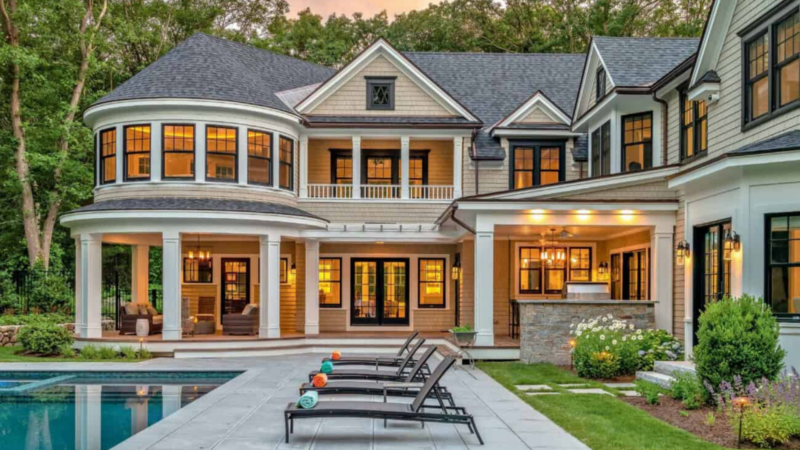 A lively backyard in Essex County showcases a stunning two-story home, vibrant patio, poolside loungers, and inviting lush gardens.