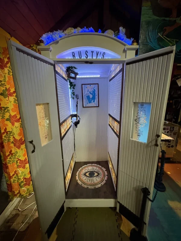 A lively "RUSTY’S" booth with doors open to all, creative panels, local art, and bold Essex spirit shining in blue lighting.