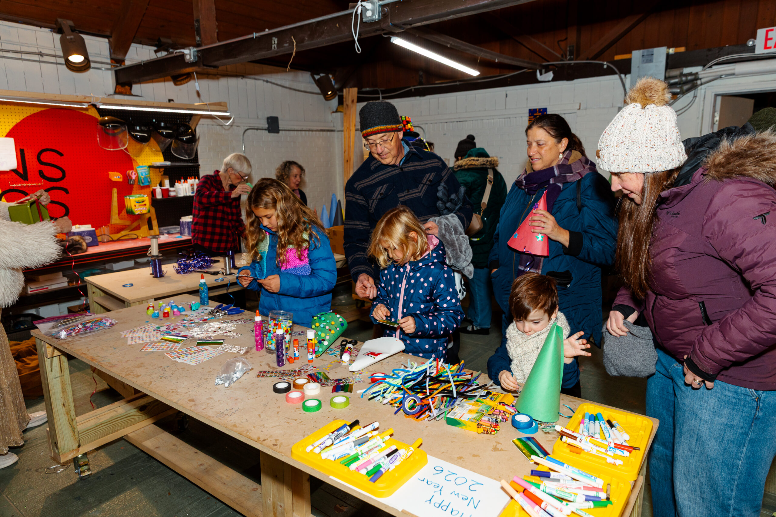 Essex County families and kids joyfully create crafts together around festive tables, celebrating community at a "Happy New Year 2025" event.