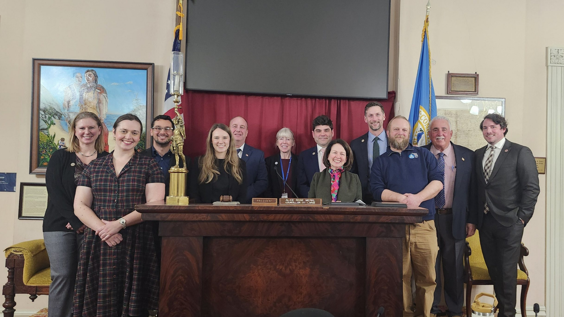 Thirteen vibrant community members from Salem MA and Essex County beam together behind a desk, celebrating local business spirit.