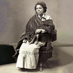 A vibrant Black woman, wrapped in a dark shawl over a bright dress, radiates resilience in this vintage Essex County-inspired portrait. Edmonia Lewis