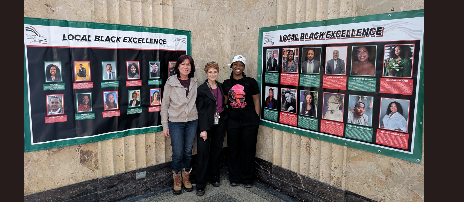 Three people gather before vibrant “Local Black Excellence” banners, celebrating creative community leaders from Essex County indoors.