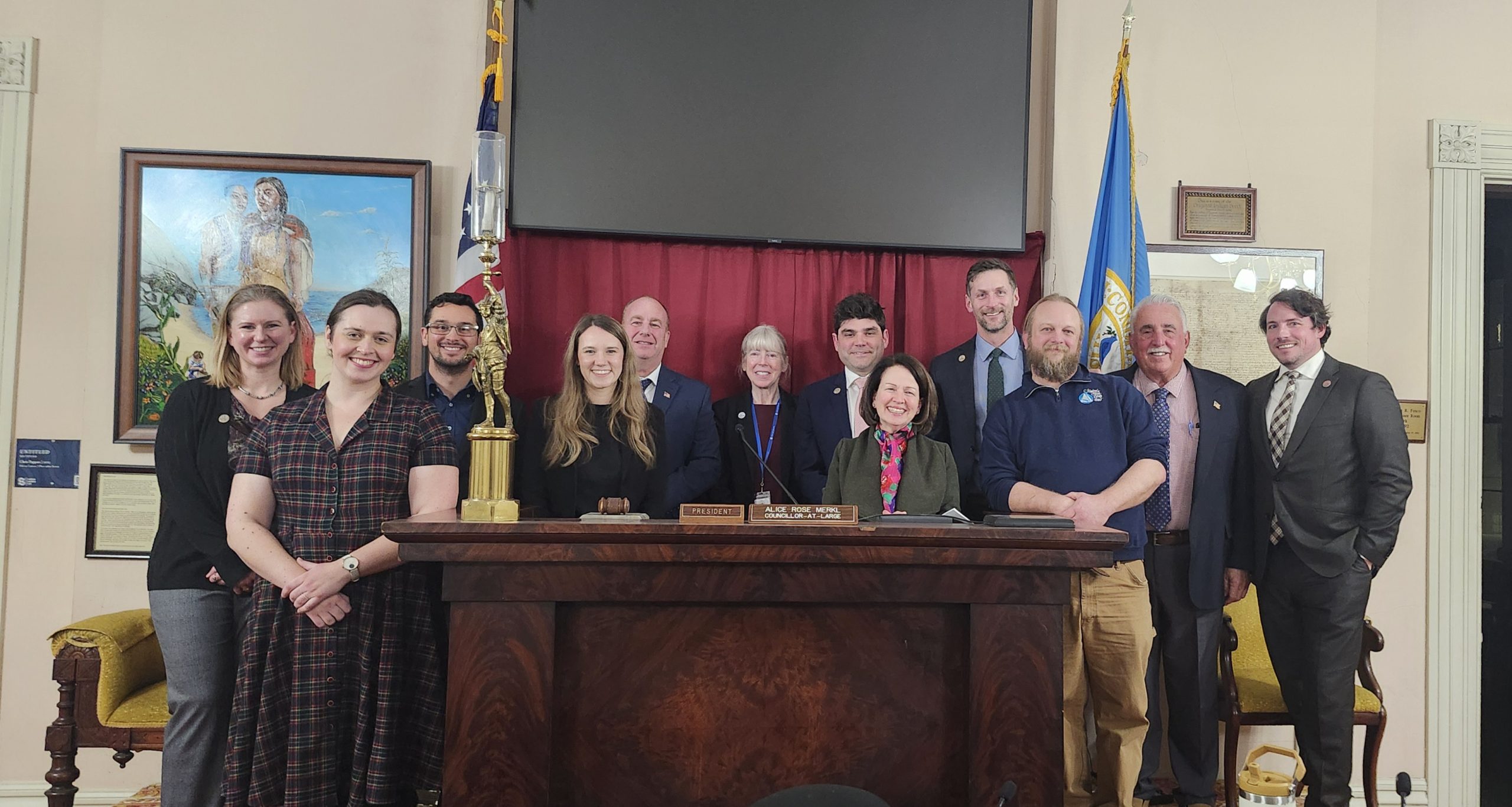 Twelve vibrant Essex County entrepreneurs gather around a desk, radiating creativity and community spirit in a formal room.