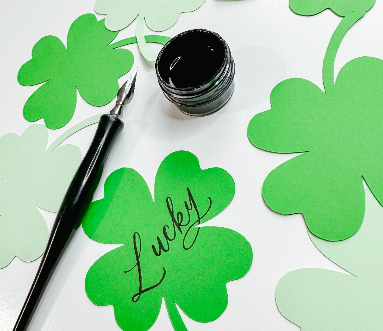 A calligraphy pen, ink jar, and vibrant green paper clovers—Essex County’s creative spirit shines with “Lucky” shared among us.