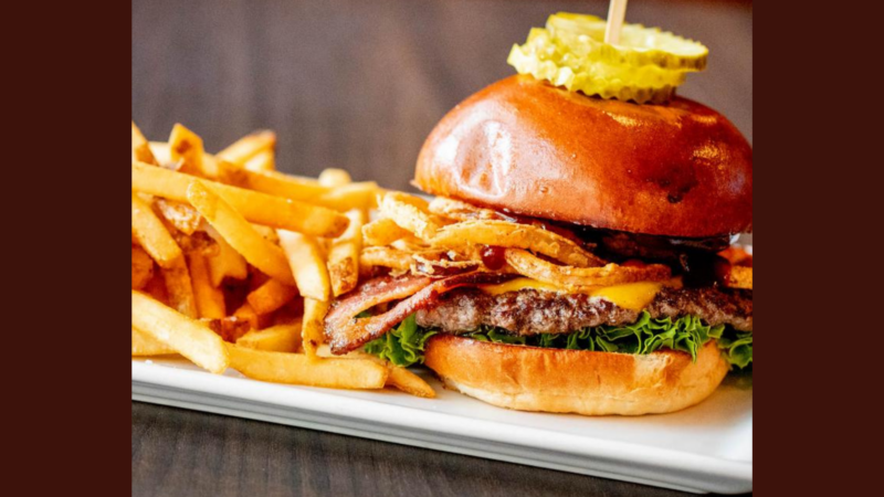 A vibrant Village Tavern burger stacked with creative toppings and fries, showcasing Essex County’s local flavor and community spirit.