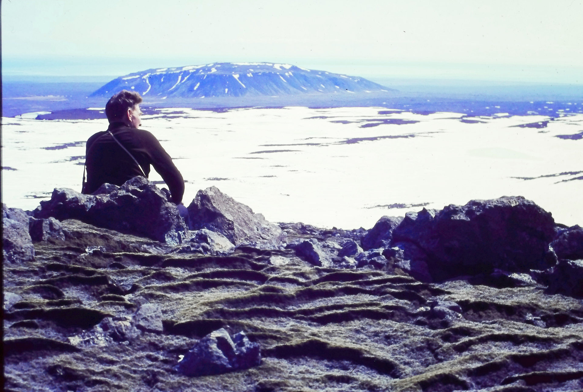 Among mossy rocks, a creative soul connects with Essex County’s snowy landscape and iconic flat-topped peak, inspiring community.