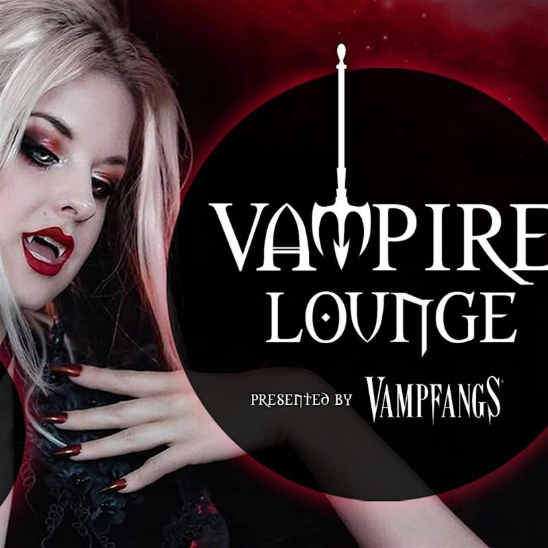 A person with pale skin, dramatic dark eye makeup, and red lipstick poses with hands raised in front of a black and red graphic that reads "Vampire Lounge presented by Vampfangs.