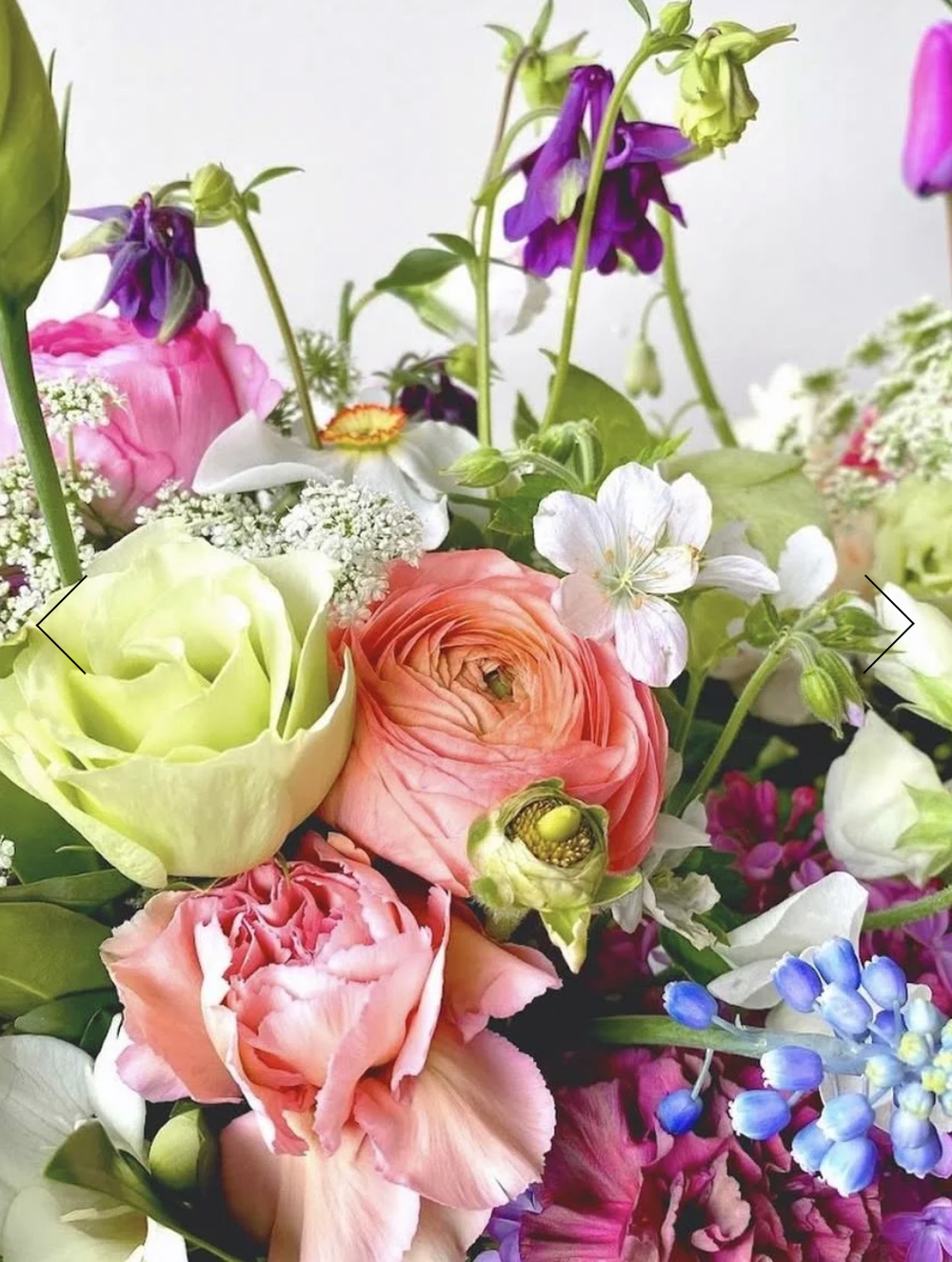 A close-up of a colorful bouquet from Fioritura Farm with fresh flowers—roses, ranunculus, carnations, and delphiniums—in pinks, peaches, greens, whites, purples, and blues; perfect for Mothers' Day or your next floral workshop.