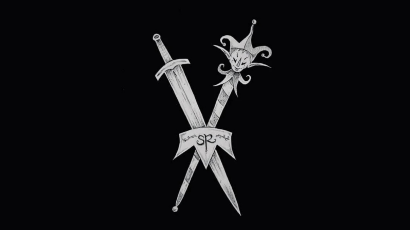 Two crossed daggers on a black background; one has a straight blade, and the other has a jester’s head as the pommel. A ribbon with "SR" and decorative writing—evoking the spirit of Salem RenFaire—is draped over the intersection.