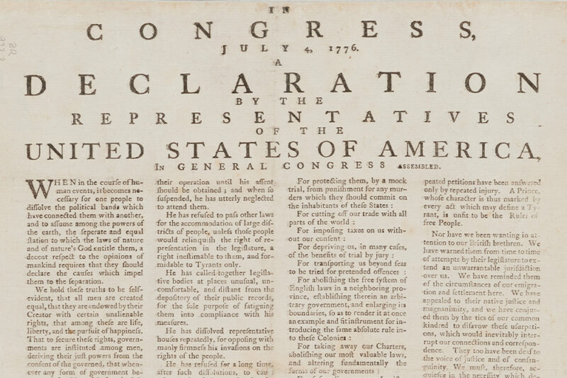 Close-up of the top portion of the United States Declaration of Independence, dated July 4, 1776, showing the heading, introduction, and part of the first paragraph in black printed text on aged paper.